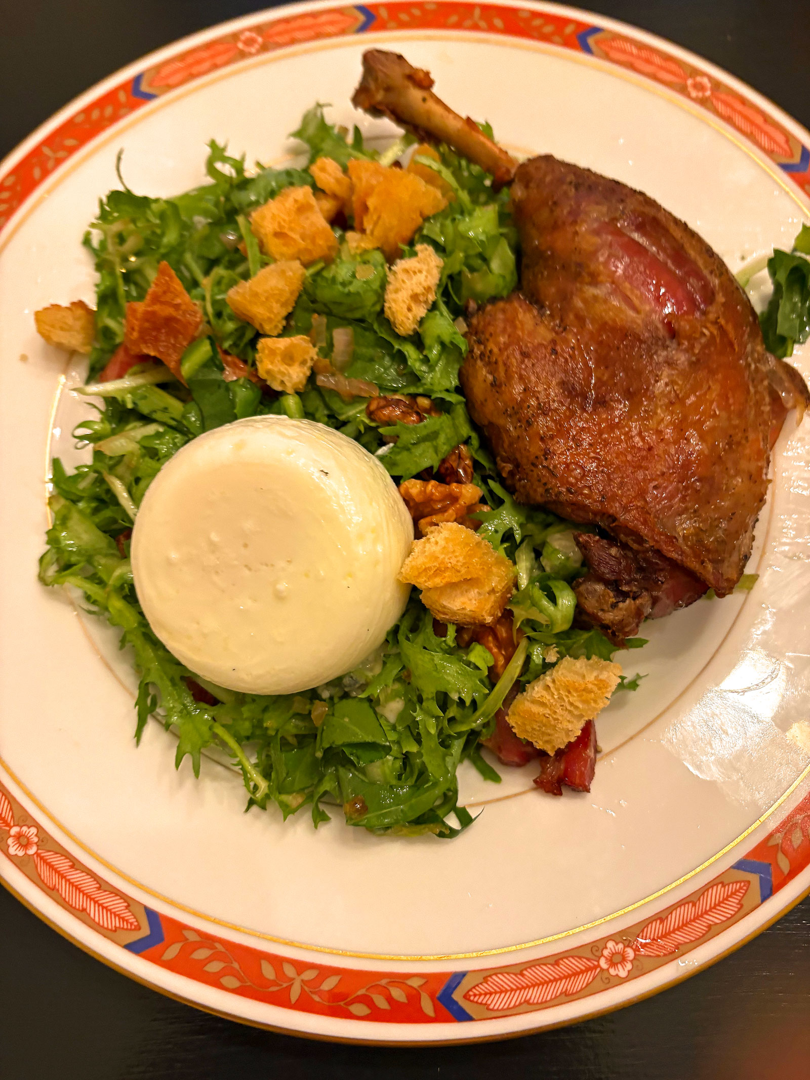 Frisée, bacon, walnuts, croutons, Roquefort, duck confit, and poached egg with hot vinegar dressing.